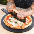 owner cutting a pizza fresh out of a gozney dome pizza oven