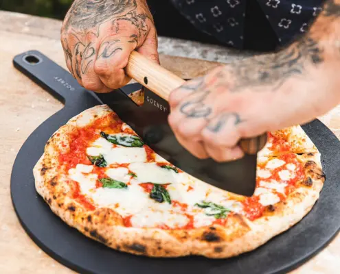owner cutting a pizza fresh out of a gozney dome pizza oven