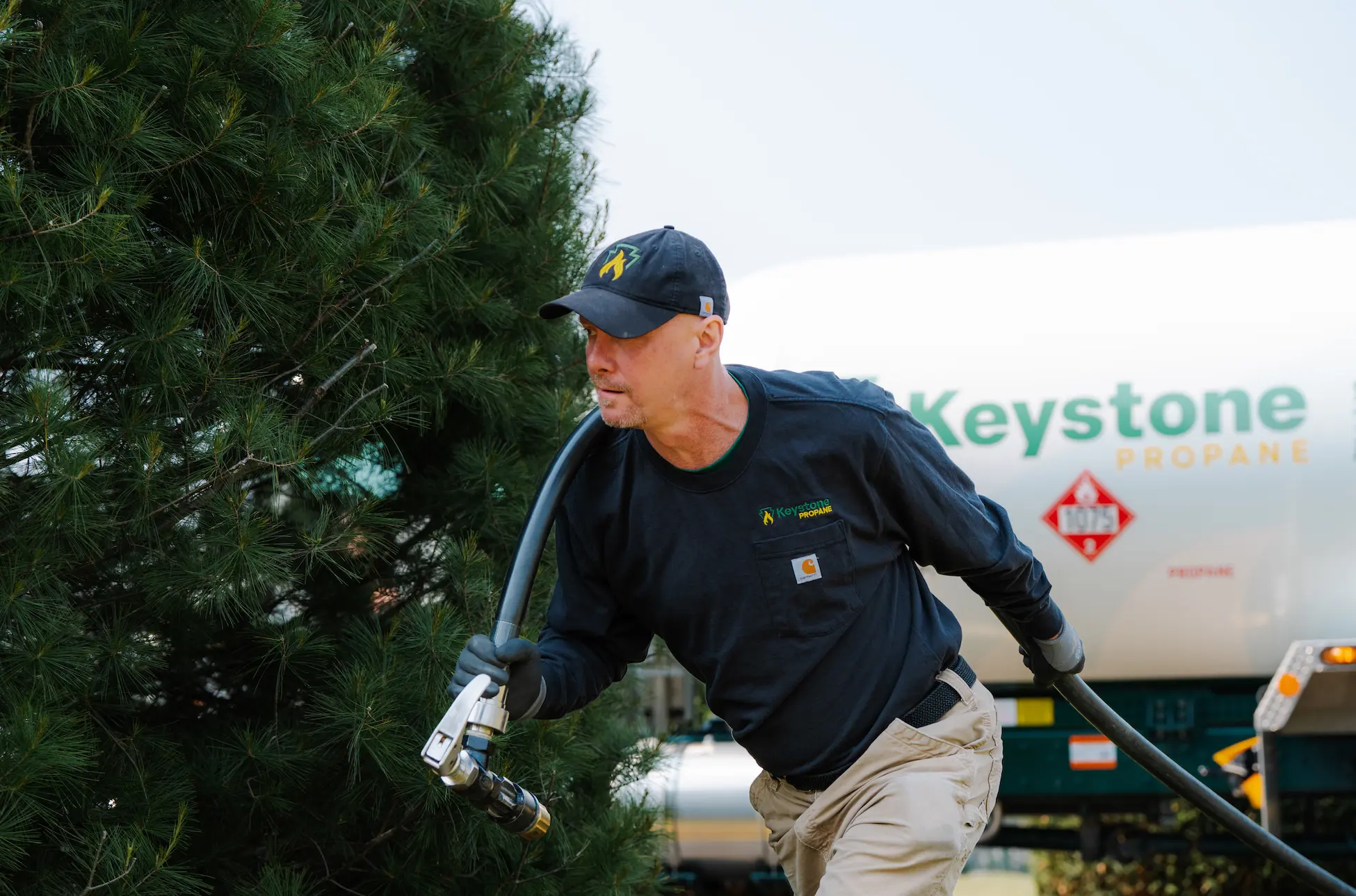 Employee pulling propane hose across lawn