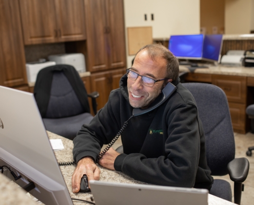 Employee on telephone and looking at computer screen smiling