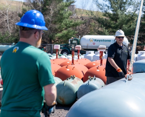 Two employees attaching tank to crane