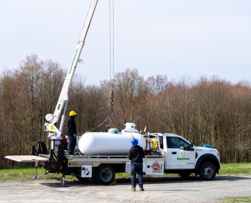 Wide angle shot of employees using crane to lift tank