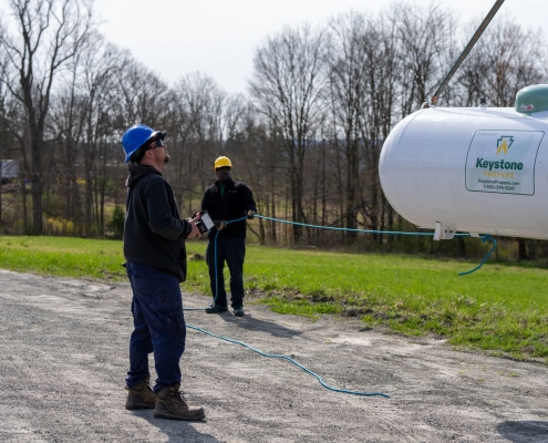 2 employees using crane to move tank into place