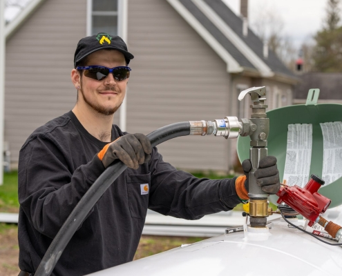 Employee filling propane tank with hose from truck