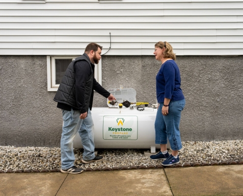 Employee showing parts of propane tank to customer