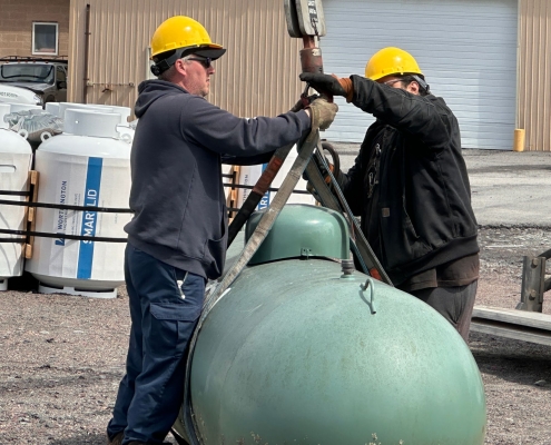 2 employees attaching tank to crane