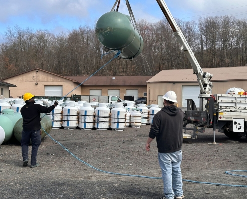 Two employees moving propane tank with crane