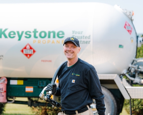 Employee smiling in front of truck with delivery hose