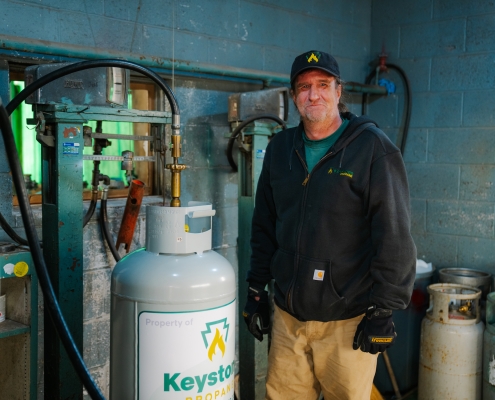 Employee standing next to propane cylinder