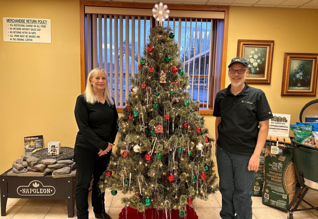 2 employees standing next to Christmas tree