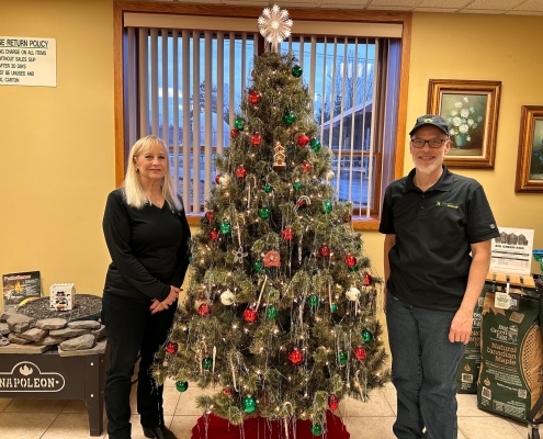 2 employees standing next to Christmas tree