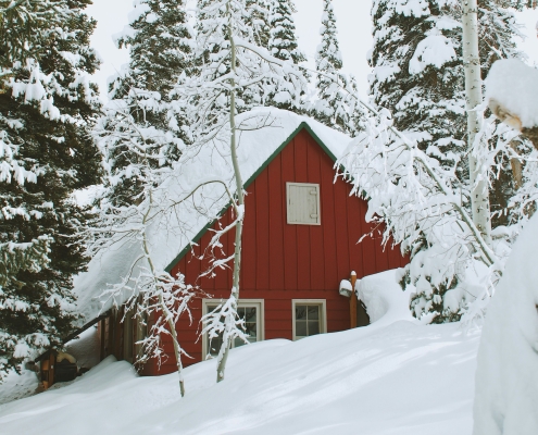 Red home in the forest covered in snow