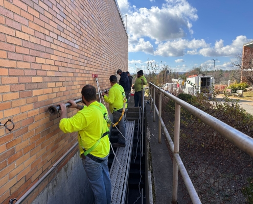 Wide, group shot of techs sliding pipe into place