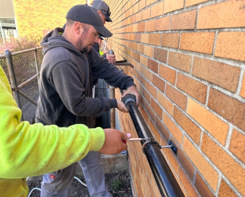 Employees putting black pipe into place