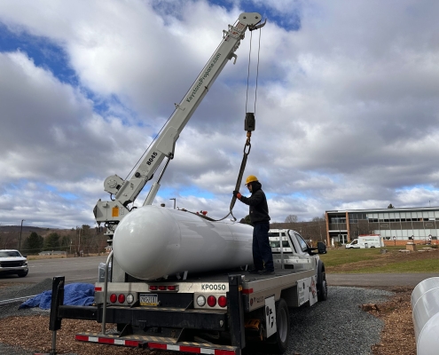 Employee attaching tank to crane on the back of truck