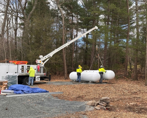 Crane lowering propane tank to the ground