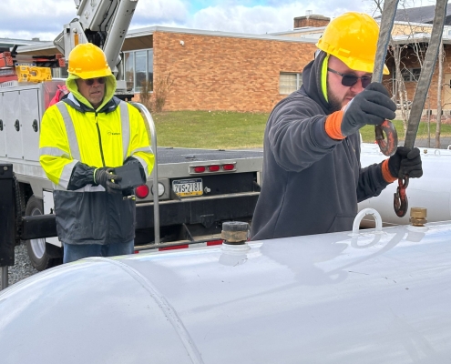 Two employees hooking tank to crane