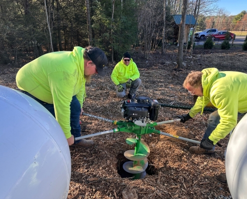 Employees using auger to dig hole.