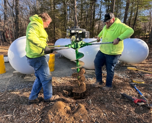 Employees using auger to dig hole.